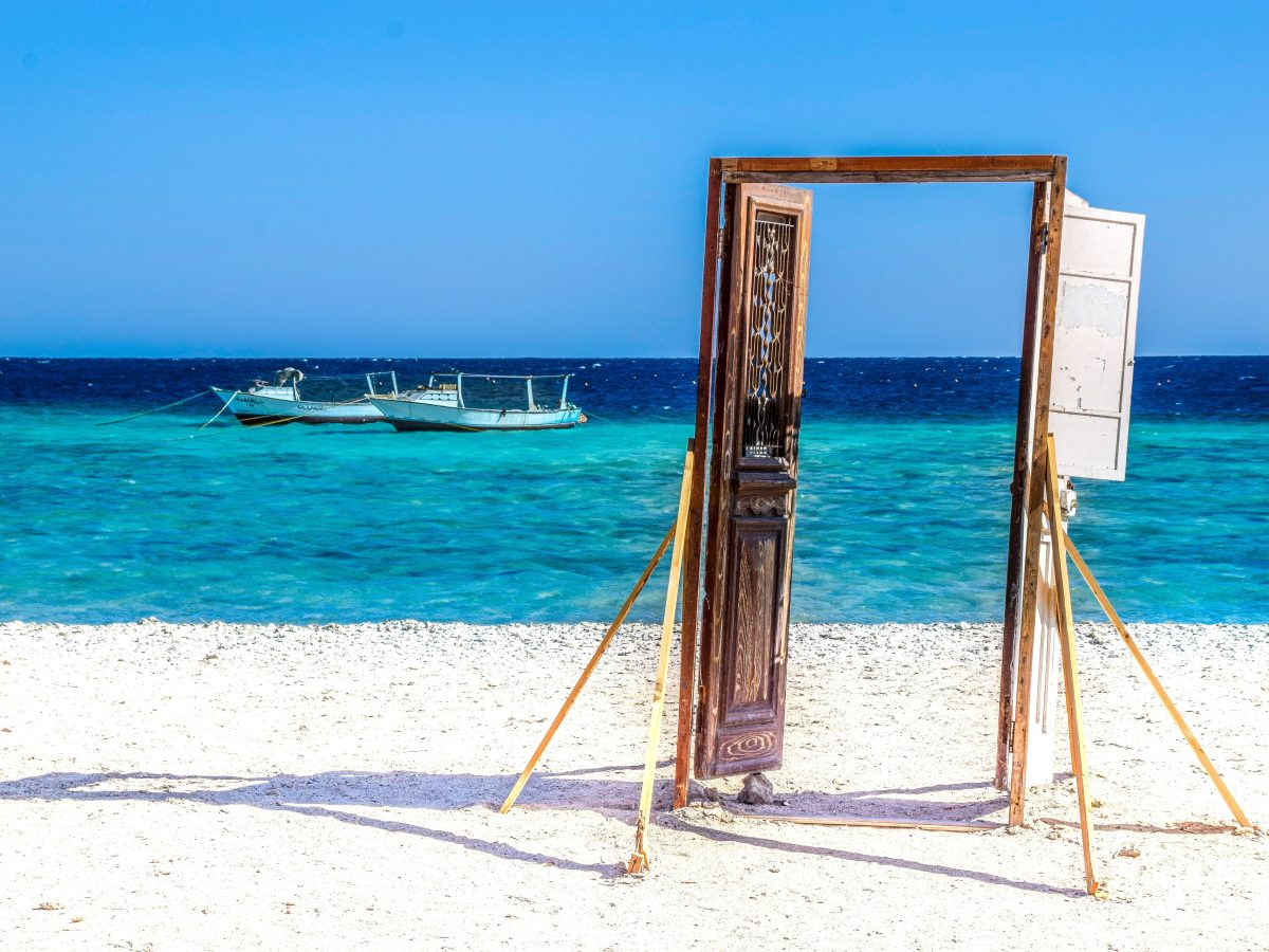 Turquoise Red Sea water and traditional wooden doorway on the beach