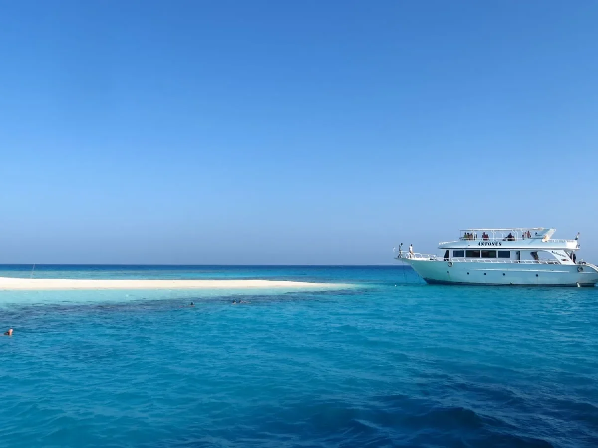 Boat beside a white sandbank in clear sea water