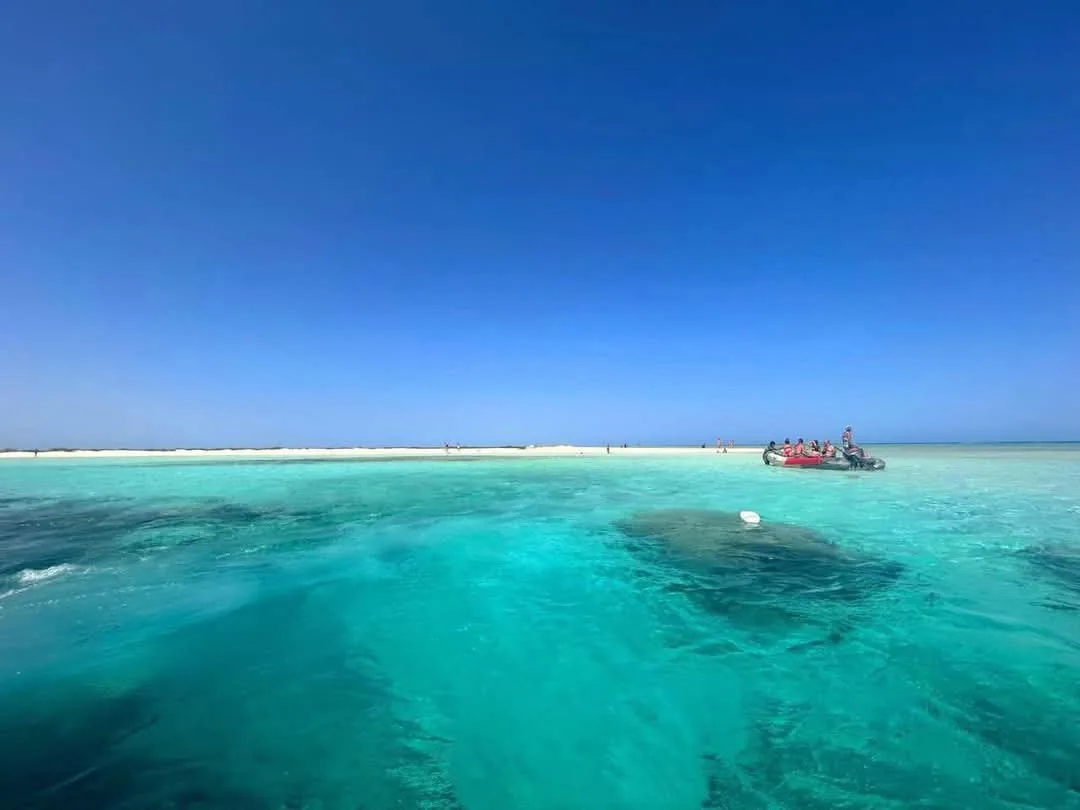 Turquoise water and a boat near a sandy island