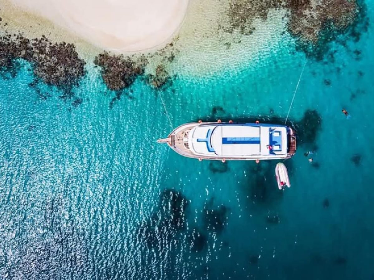 Aerial view of a boat moored beside a turquoise coral reef